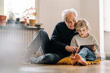 Großvater liest mit Enkelkind ein Buch auf dem Boden